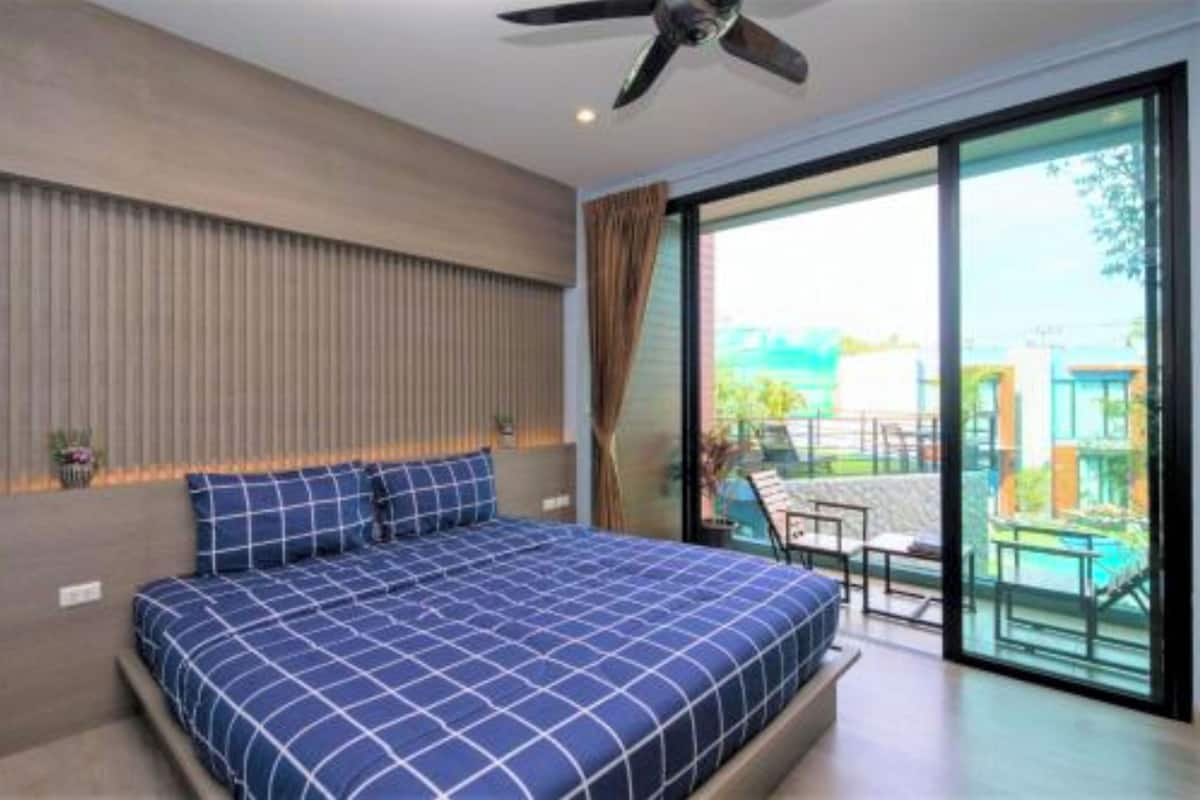 Ein Schlafzimmer mit einem großen Bett, einem Deckenventilator und einer Glastür zum Außenbereich.