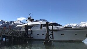 A white yacht docked at a pier with a mountainous backdrop. - Pacific Jemm - Luxury Super Yacht (Queenstown)