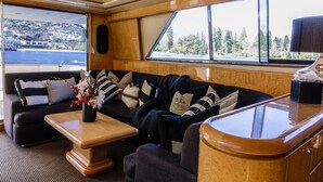 A cozy cabin with a sofa, a small table, and a window offering a view of a town and water. - Pacific Jemm - Luxury Super Yacht (Queenstown)