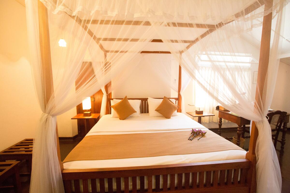 A bed with a canopy, pillows, and a bedside table with a lamp.