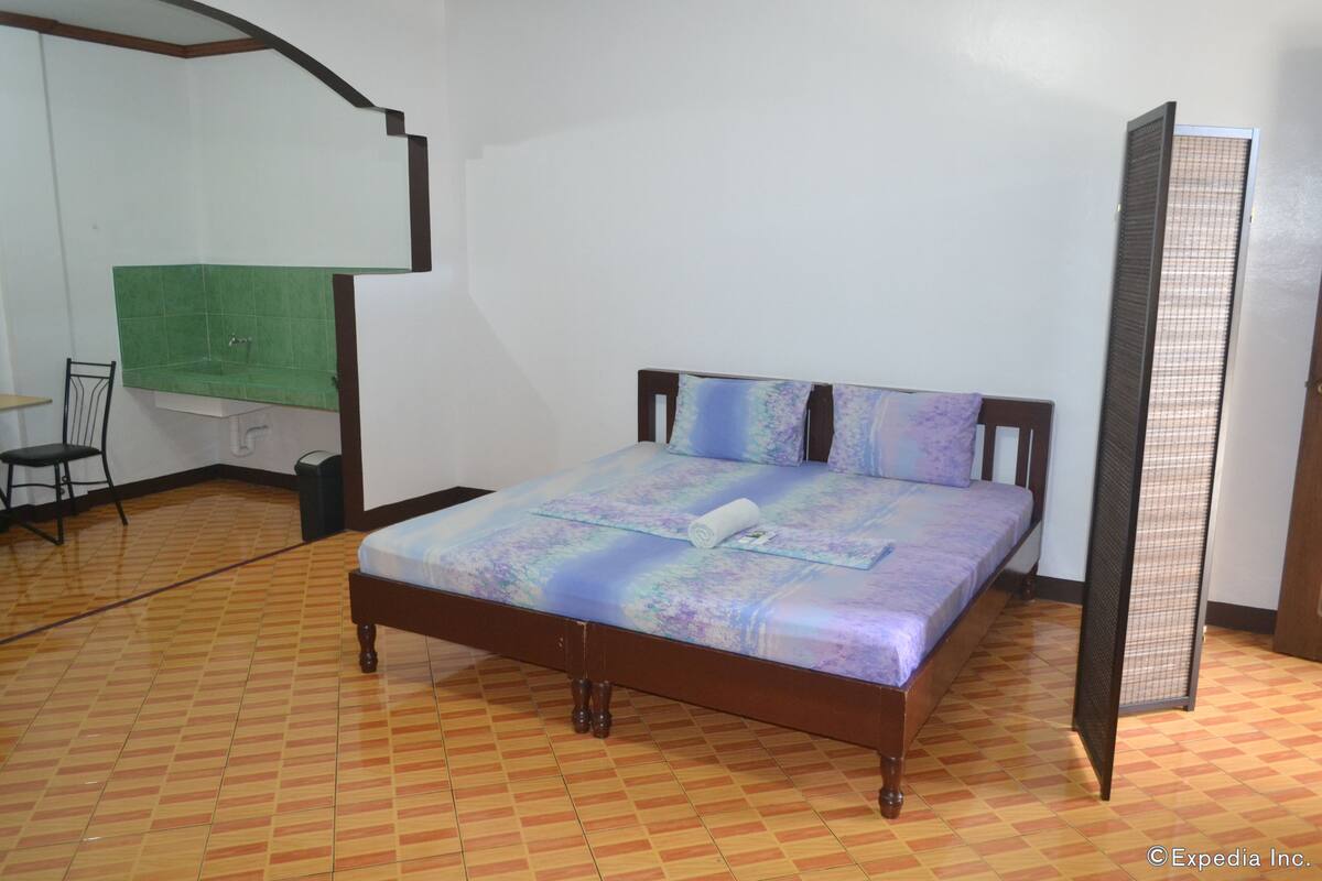 Ein Schlafzimmer mit Bett, Stuhl, Nachttisch und grüner Wand.