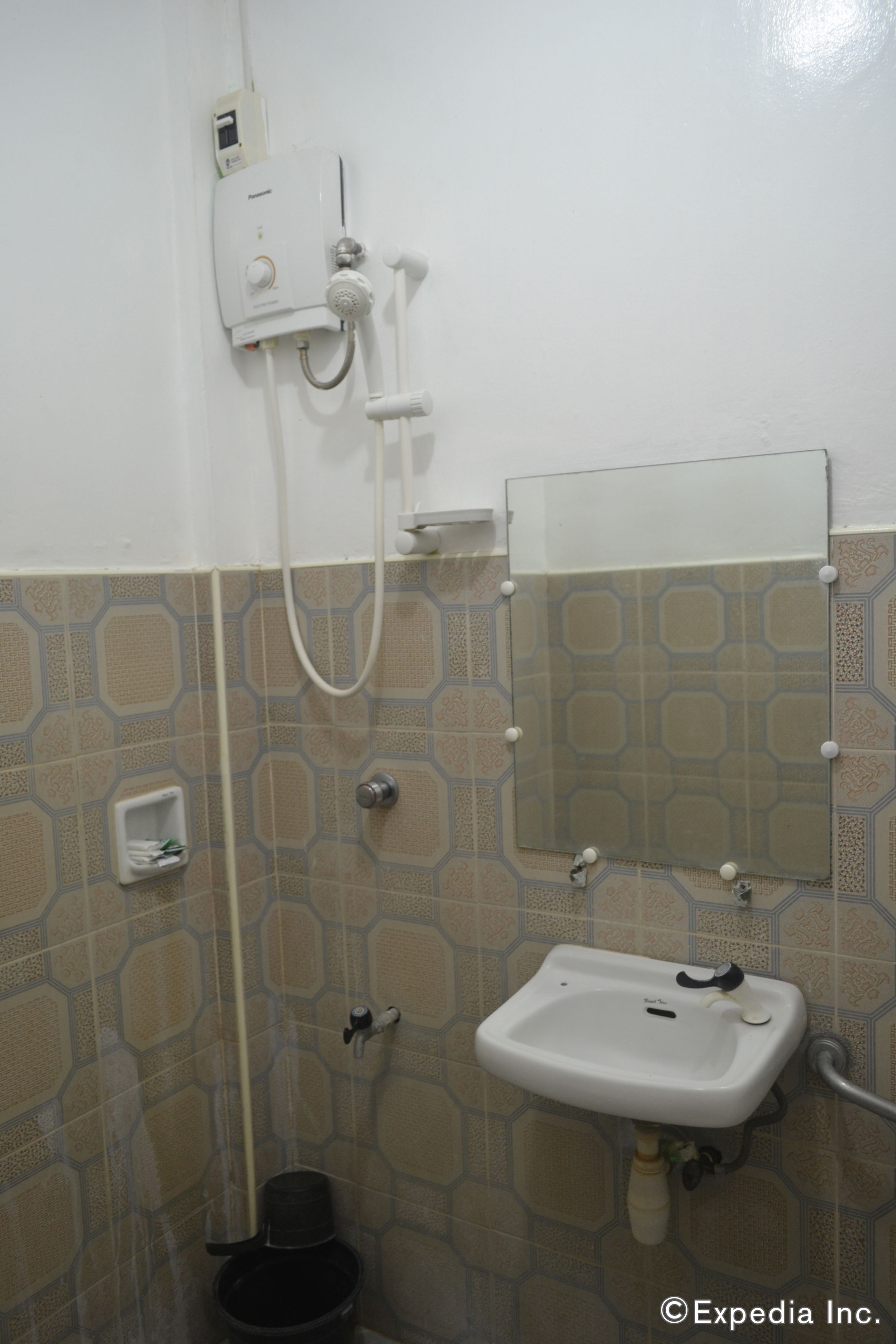 A bathroom with a white sink, a mirror, and a shower unit.