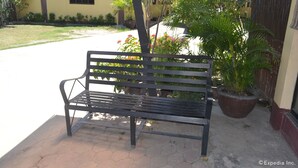 A bench in a courtyard with a potted plant and a building in the background. - Antonio's Apartelle & Suites (General Santos)