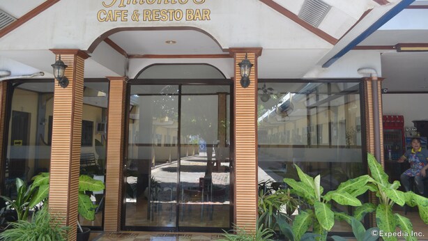Antonio's Cafe & Resto Bar entrance with glass doors, potted plants, and a clear view of the street outside. - Antonio's Apartelle & Suites (General Santos)