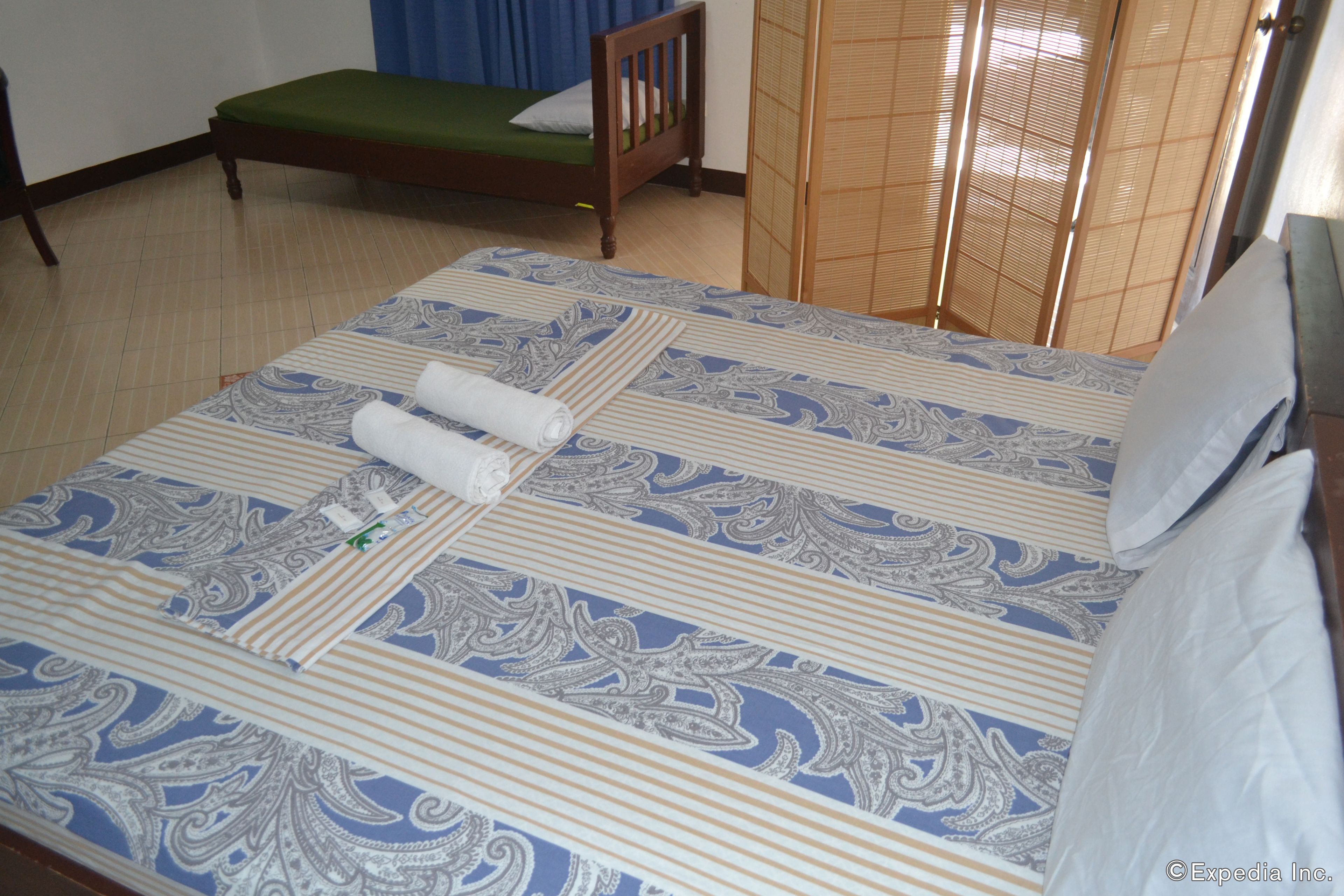 A neatly made bed with a patterned bedspread, a wooden headboard, and a green mattress.