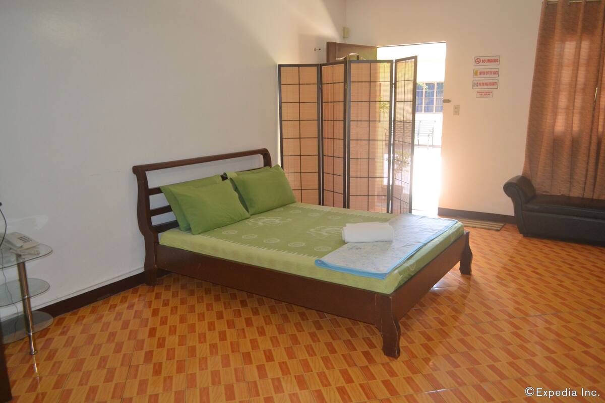 Ein Zimmer mit einem Bett, einem Glastisch, einer Trennwand und einem Stuhl.