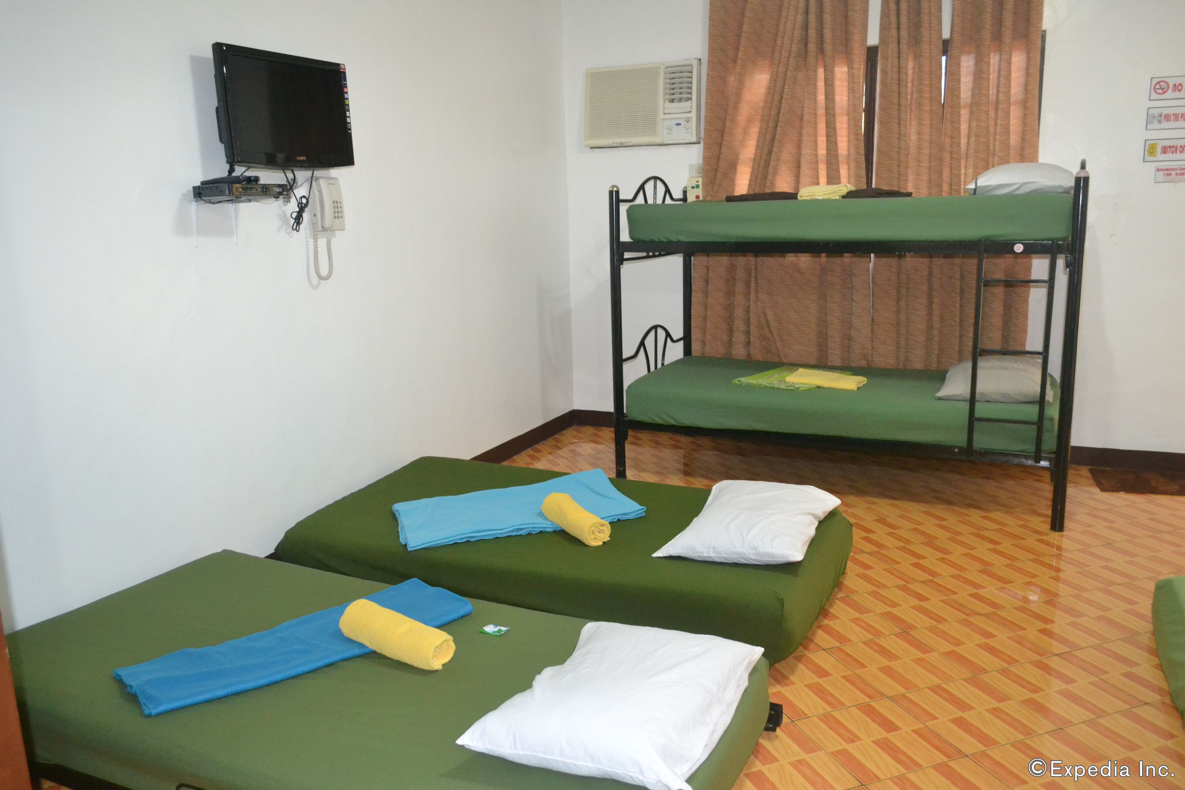 A room with bunk beds, a flat-screen TV, a telephone, and a wall-mounted air conditioner.