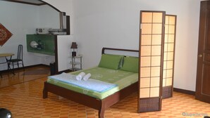 A room with a bed, a desk, a chair, a small table, and a cabinet. - Antonio's Apartelle & Suites (General Santos)