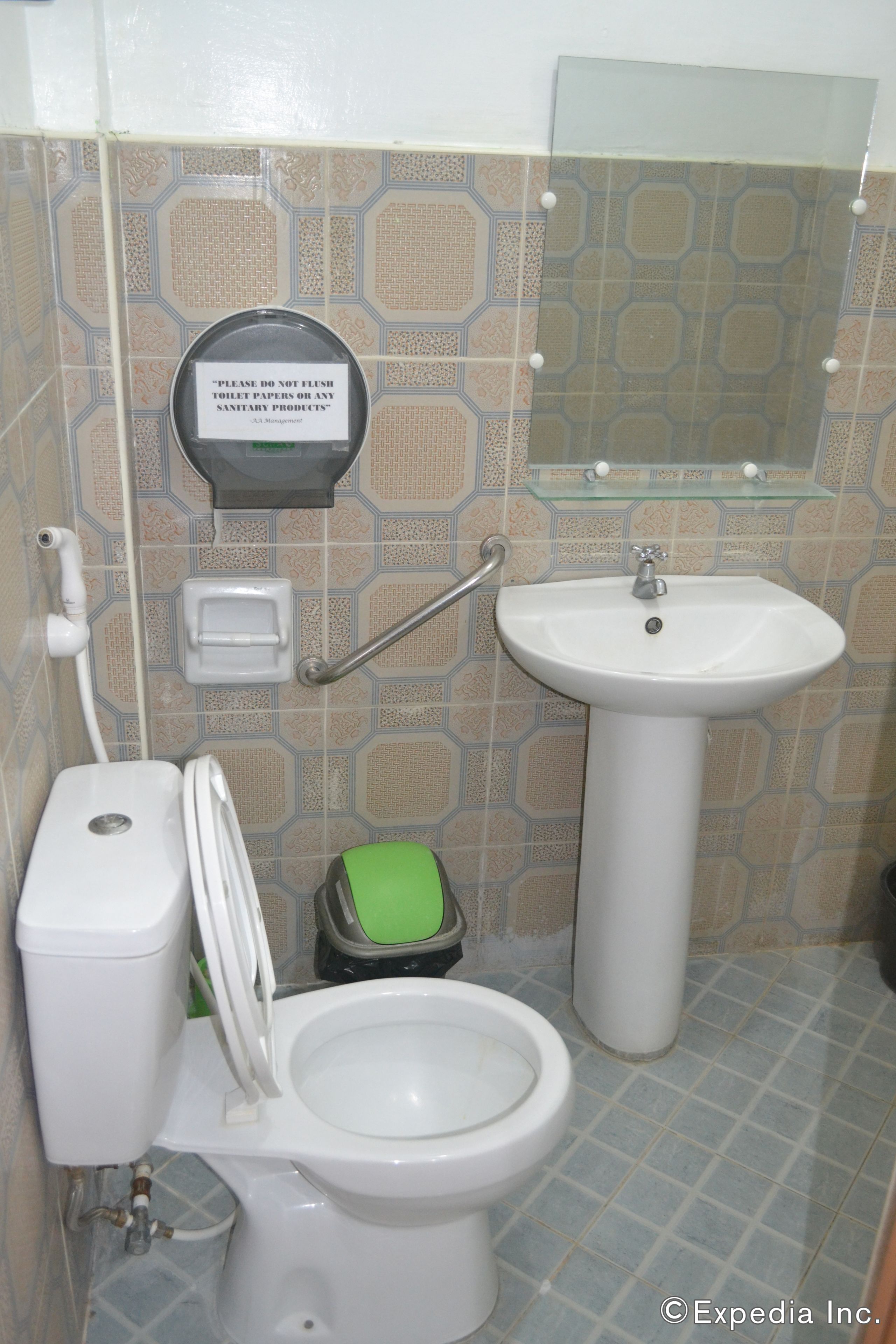 A bathroom with a toilet, sink, and a trash bin.