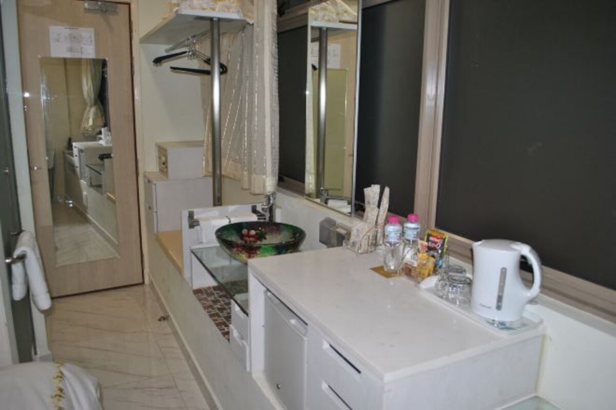 Un baño con lavamanos blanco, un espejo, toallero y zona de ducha.
