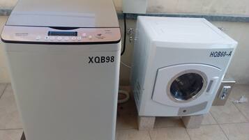 Two large industrial machines, one labeled XQB98 and the other HQB60-A, placed on a tiled floor next to a wall with a control panel above them.