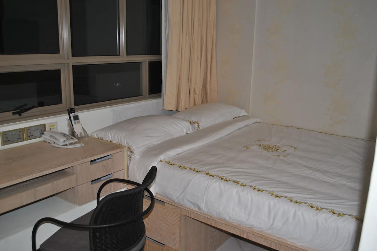 A bedroom with a bed, a desk with a telephone, and a chair.