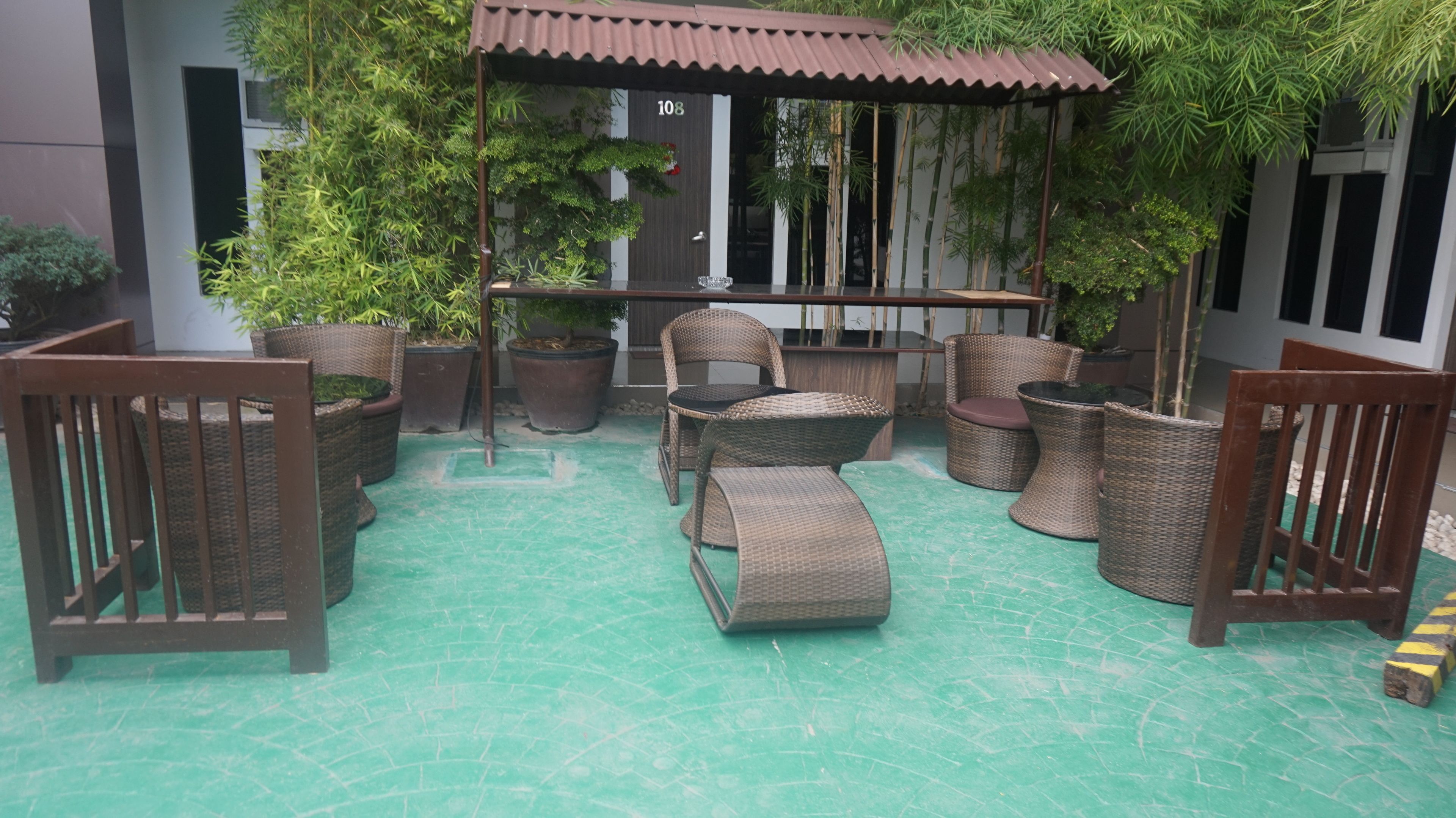 A covered outdoor seating area with wicker furniture and a tiled floor.