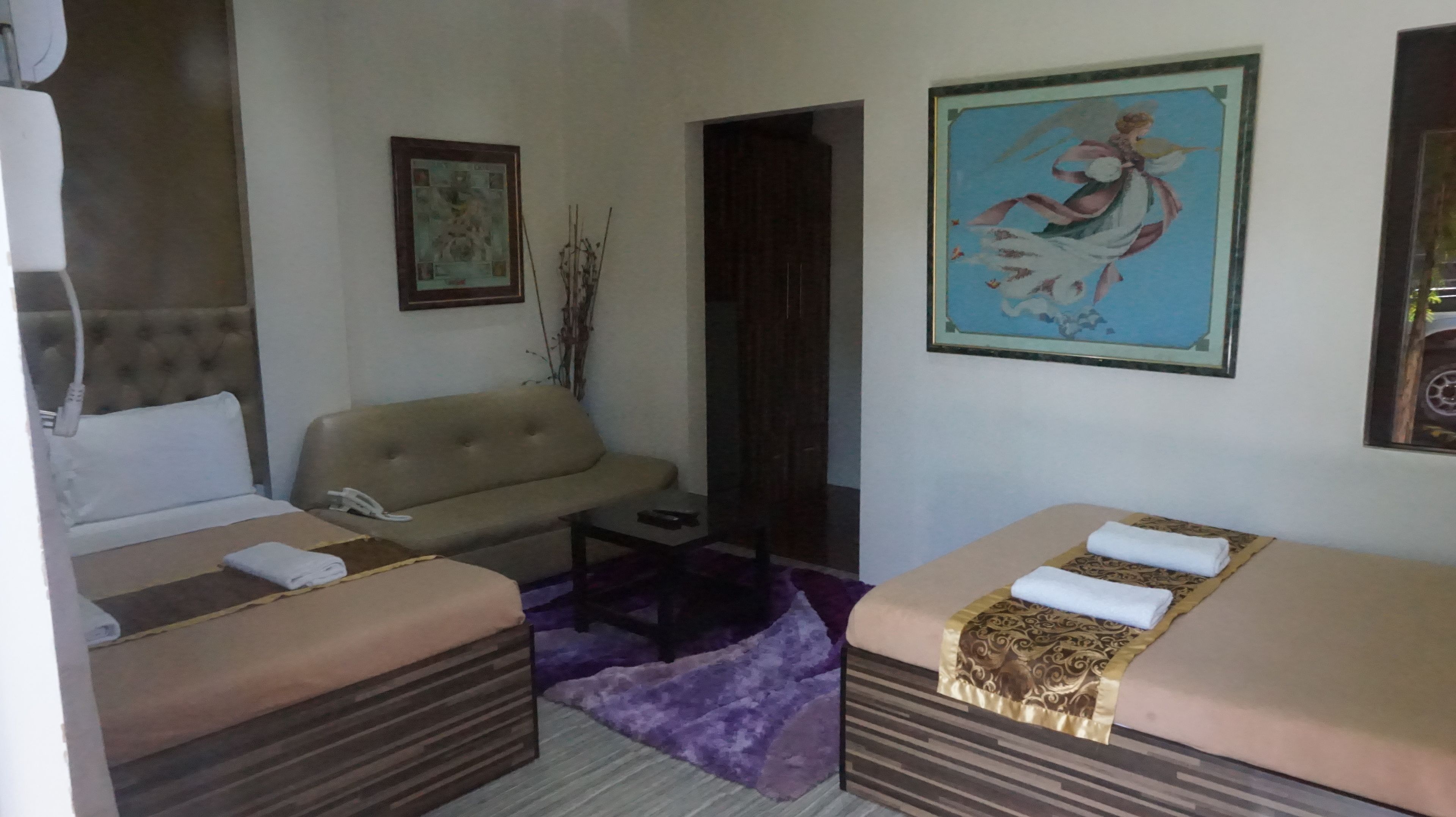 Une chambre d’hôtel avec deux lits, un canapé, une petite table et un tableau au mur.