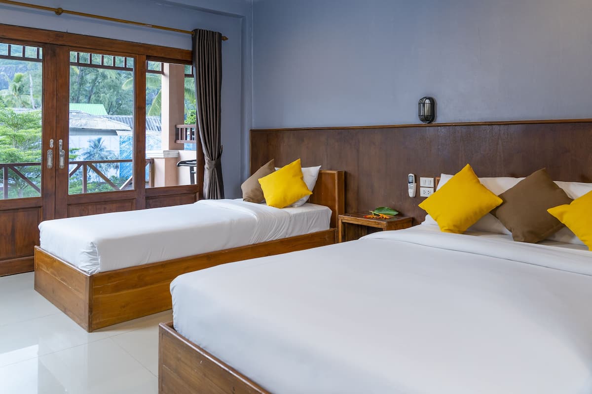 A hotel room with two beds, wooden headboards, and a view of the outdoors.