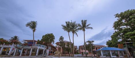 A beachfront property with multiple buildings, palm trees, and a sandy beach.