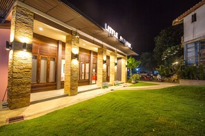 Little House offers a serene entrance with a beautifully maintained lawn and a warm, inviting glow.