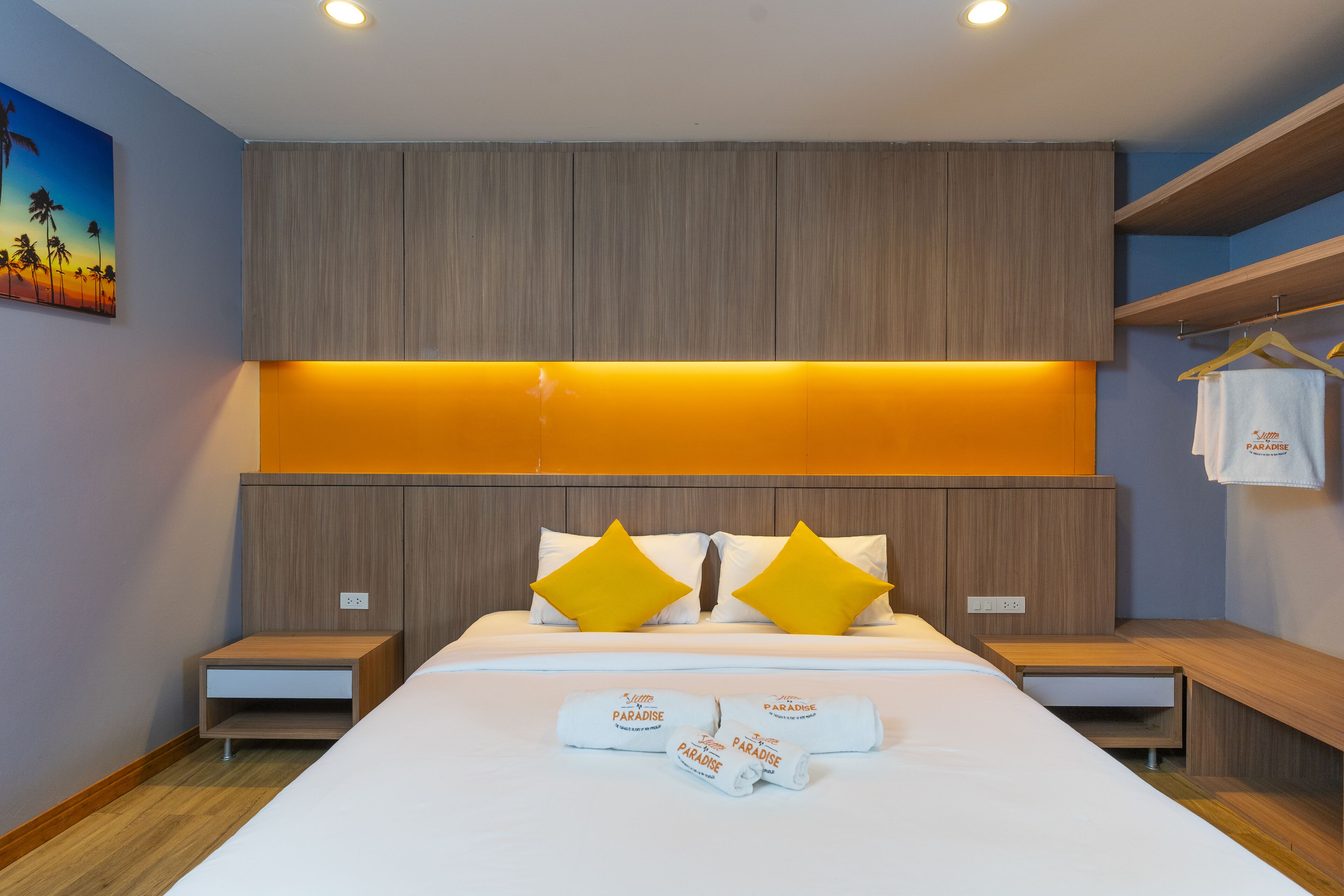 A modern hotel room with a large bed, wooden headboard, and two nightstands.