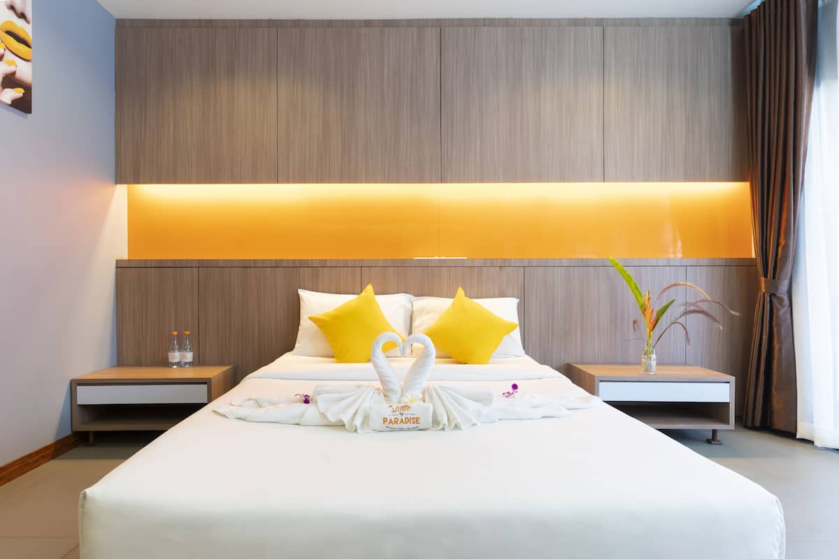 A hotel room with a large bed, two nightstands, a wall-mounted lamp, and a decorative towel arrangement.