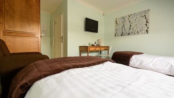 A hotel room with two beds, a wooden wardrobe, a desk with a chair, a flat-screen TV, and a wall-mounted artwork.