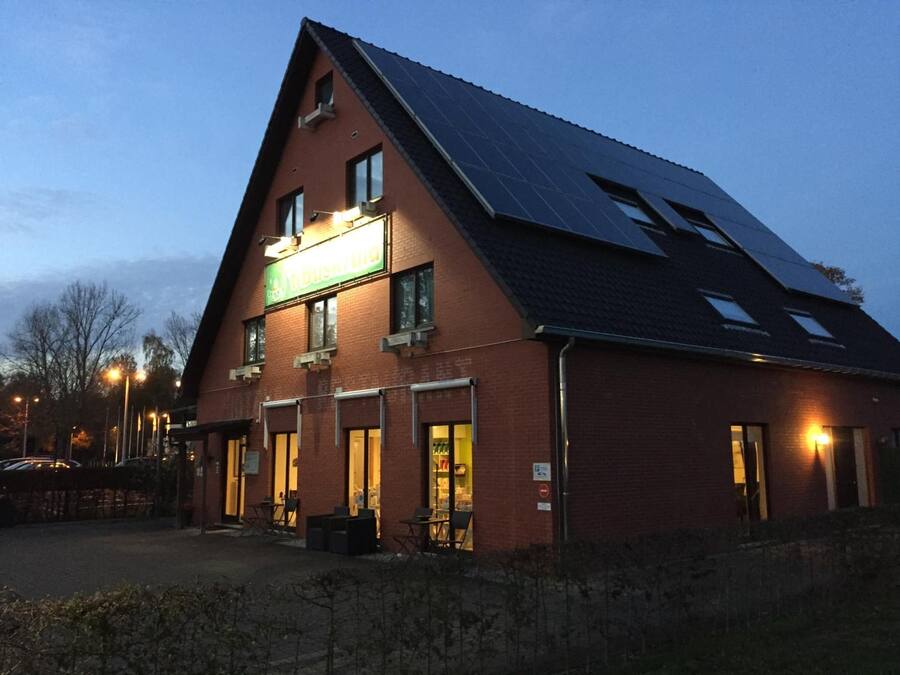 A two-story building with a sloped roof, solar panels, and a sign indicating a restaurant or cafe.