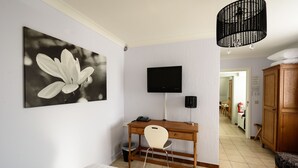 Quarto com cama, escrivaninha com cadeira, televisão e uma grande pintura de flores na parede.