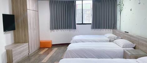 A hotel room with two beds, a TV, and a window with curtains.