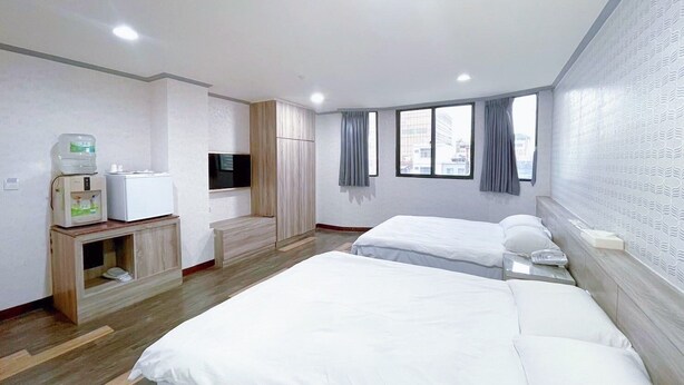 A hotel room with two beds, a TV, a minibar, and a window with curtains. - A22 Wei Lu Hotel (Taoyuan City)