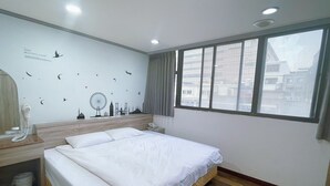A hotel room with a large bed, a wooden headboard, a wall with cityscape decals, a window with a view of buildings, and a telephone on the nightstand. - A22 Wei Lu Hotel (Taoyuan City)