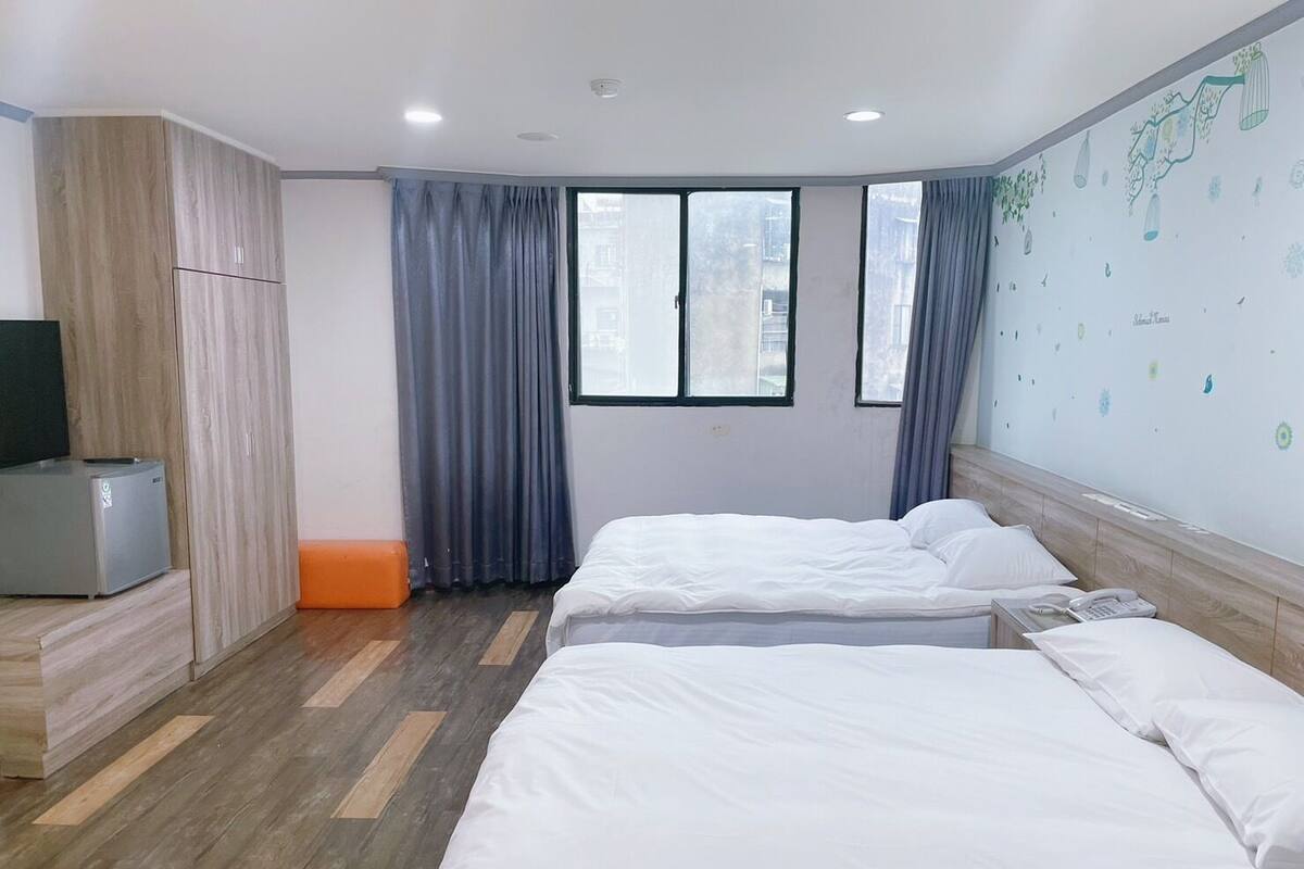 A hotel room with two beds, a TV, and a wardrobe.