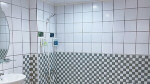 A bathroom with white tiles, a checkered shower wall, a sink, and a mirror. - A22 Wei Lu Hotel (Taoyuan City)