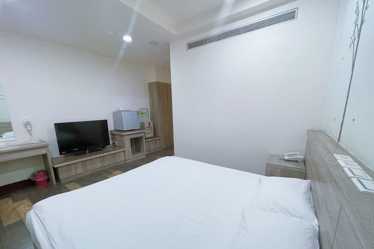 A hotel room with a bed, a television, a desk, and a wardrobe.