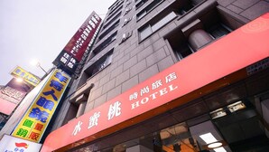 A hotel with a prominent red sign and multiple colorful advertisements on the building facade. - Peach Hotel (Hsinchu)