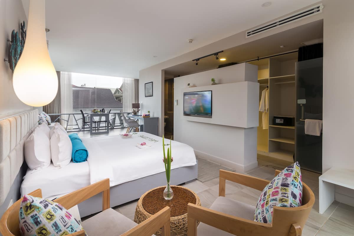 A modern bedroom with a bed, bedside tables, a TV, and a walk-in closet.