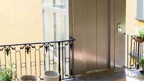 A balcony with a wrought iron railing, potted plants, and a door leading to an interior space. - B&B I Tetti Napoli (Naples)