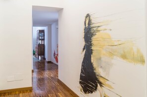 A hallway with a large abstract painting on the right wall and a wooden floor. - B&B I Tetti Napoli (Naples)