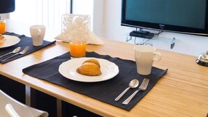 A breakfast setup with croissants, orange juice, and coffee on a wooden table. - B&B I Tetti Napoli (Naples)