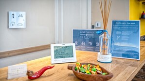 Een houten receptiebalie met een digitale klok, een bordje met 'Giacomo Sorrento', een decoratieve rietverspreider en een kleine schaal met kleurrijke snacks.