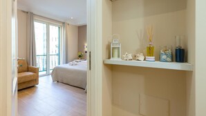 Een hotelkamer met een bed, een bank, een balkon met uitzicht en een plank met decoratieve objecten.