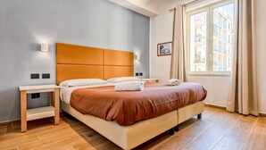 Een moderne hotelkamer met een groot bed, nachtkastje, een raam met gordijnen en een wandlamp.