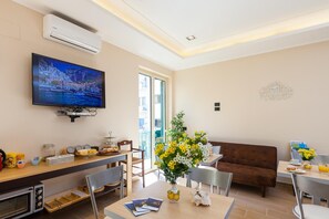 Un salon moderne doté d’un téléviseur à écran plat, d’un canapé, d’un coin repas et d’une grande fenêtre.