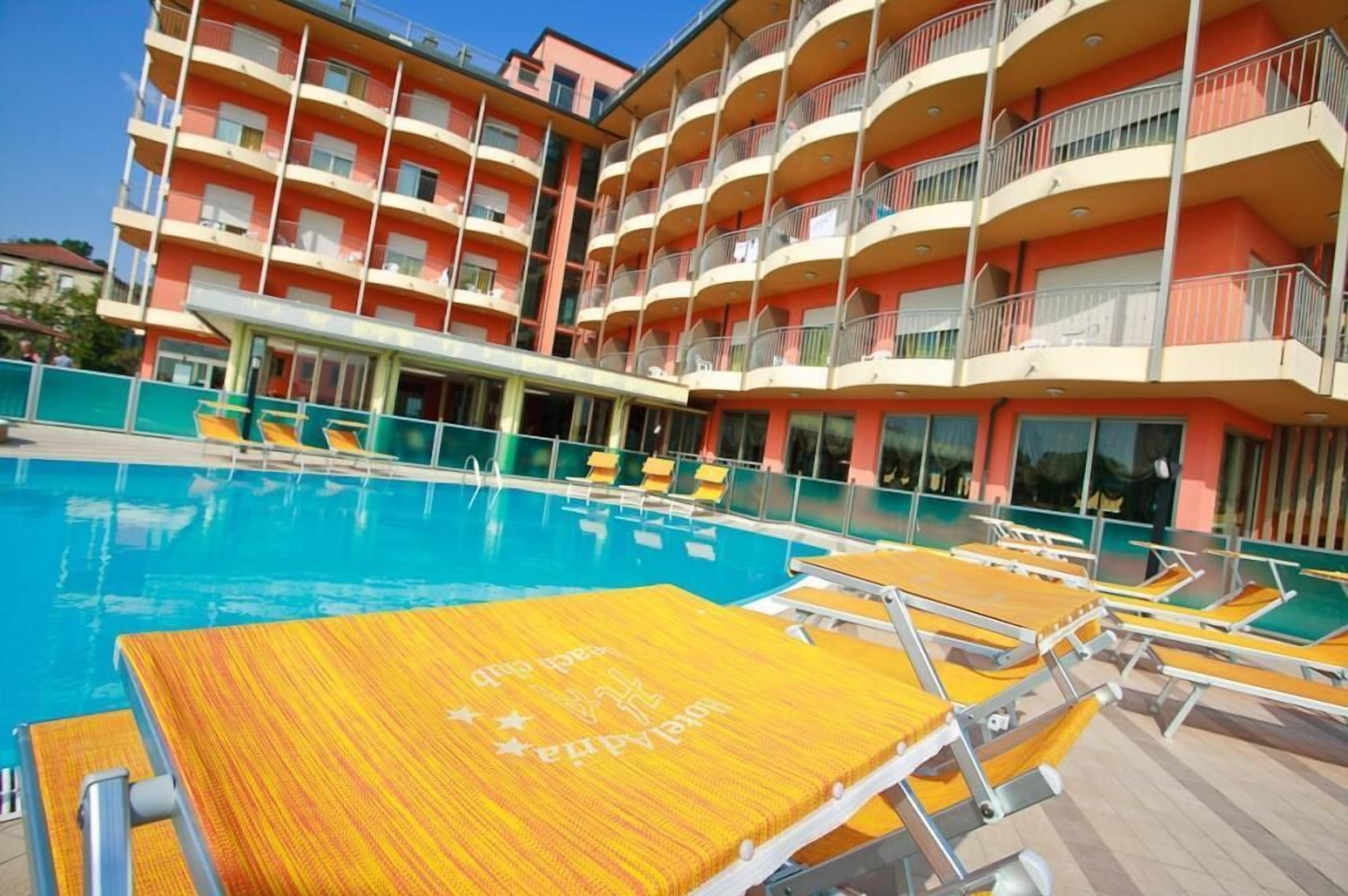 Un hotel a più piani con piscina, area salotto all'aperto e balconi.