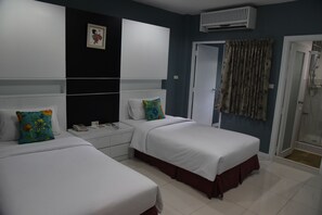 A hotel room with two beds, a white wardrobe, a bedside table with a phone, and a shower area. - Fairtex Express (Pattaya)