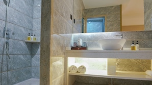 Un baño moderno con un lavabo grande, ducha y paredes de mármol.