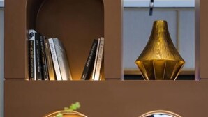A modern interior with a bookshelf, a decorative lamp, a television, and a floral arrangement. - Paco Hotel Tiyuxilu Metro Guangzhou (Guangzhou)