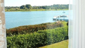 A view of a lake with a dock and a small building, surrounded by greenery and trees. - Hotel Hp Park (Poznan)