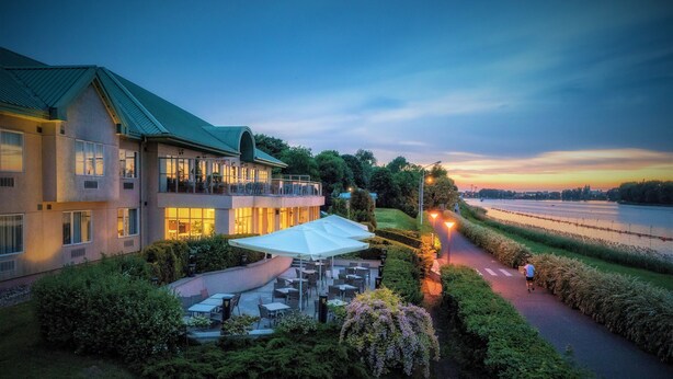 A hotel with outdoor seating and a view of a river. - Hotel Hp Park (Poznan)