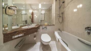 A modern bathroom with a double sink vanity, a toilet, a bathtub, and a shower.