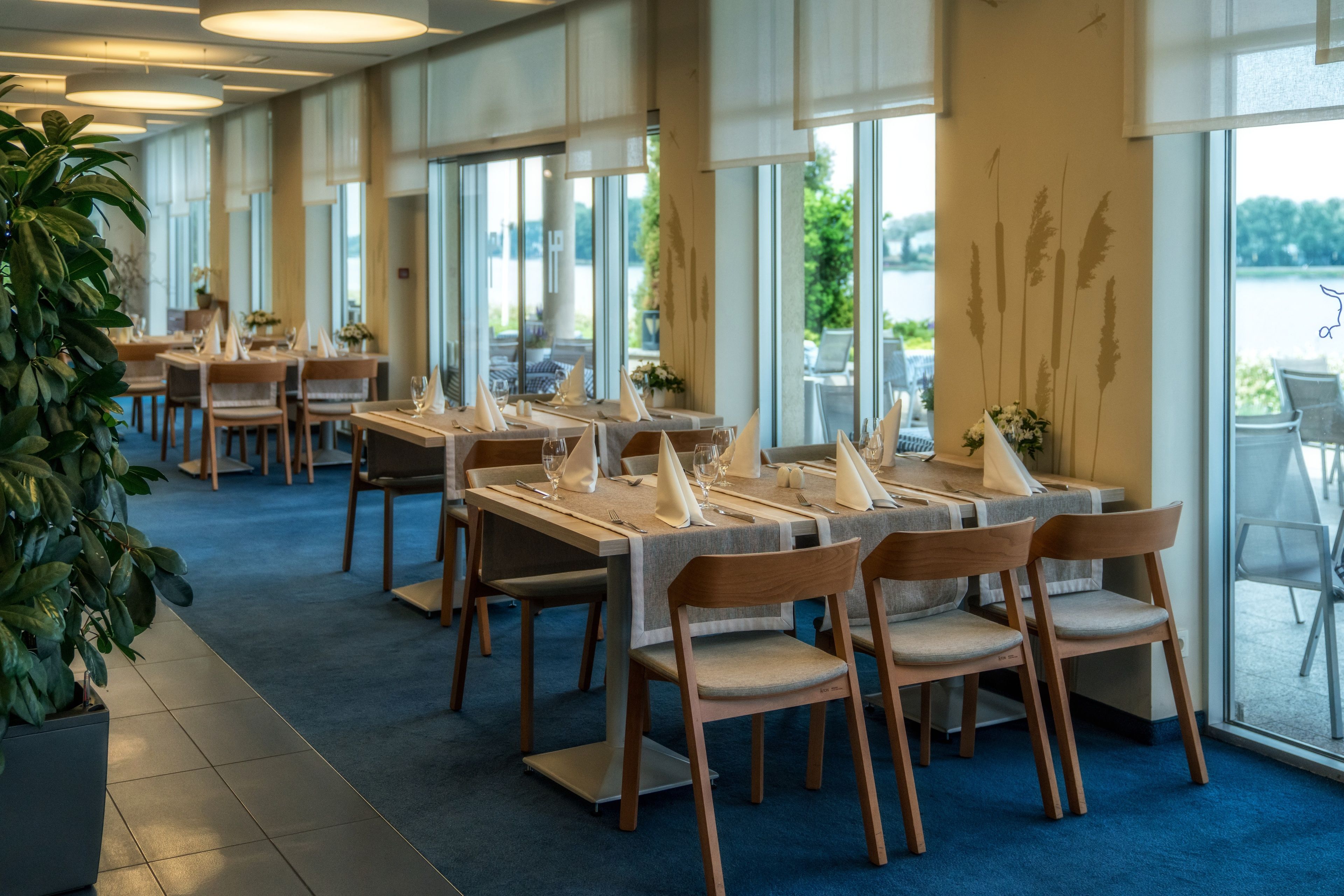 A restaurant with tables set for dining, large windows, and a view of the outdoors.