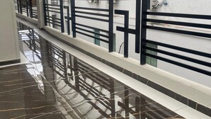 A corridor with a reflective floor, a black and white railing, and air conditioning units on the wall. - Hotel Family (São Paulo)
